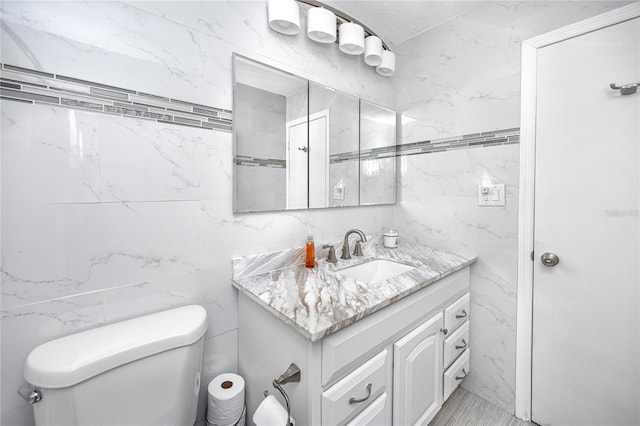 bathroom featuring vanity, tile walls, and toilet