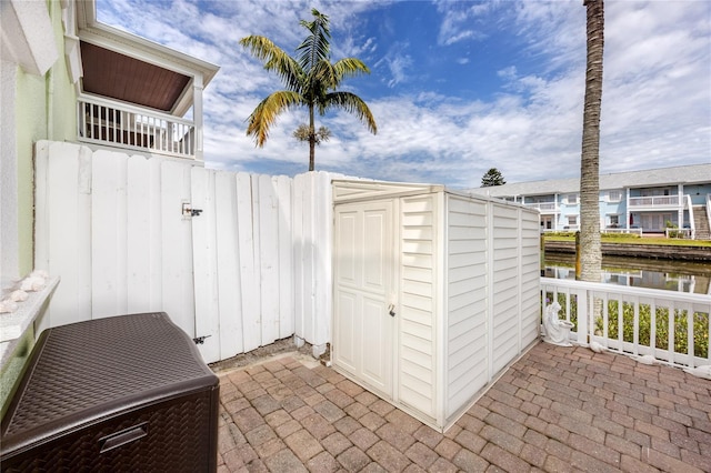 view of patio with a storage shed and a water view