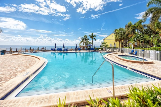 view of pool with a water view and a hot tub