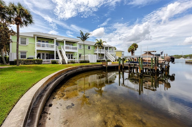 dock area featuring a balcony, a lawn, and a water view