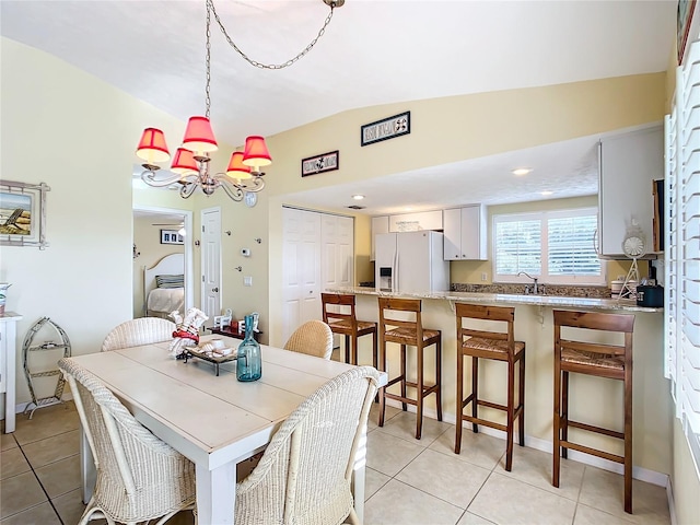 tiled dining space with lofted ceiling, sink, and an inviting chandelier