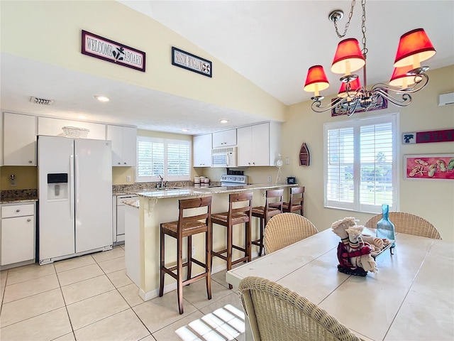 dining space featuring light tile patterned floors, plenty of natural light, an inviting chandelier, and vaulted ceiling