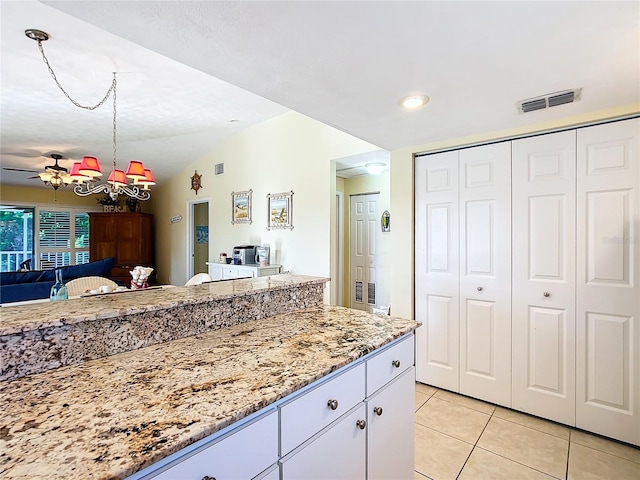 kitchen with light tile patterned floors, vaulted ceiling, light stone counters, white cabinetry, and ceiling fan