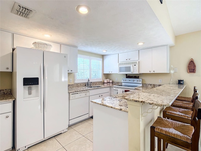 kitchen featuring a kitchen breakfast bar, white appliances, kitchen peninsula, sink, and white cabinetry