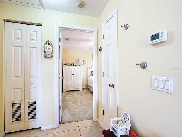 hall featuring a textured ceiling and light tile patterned floors