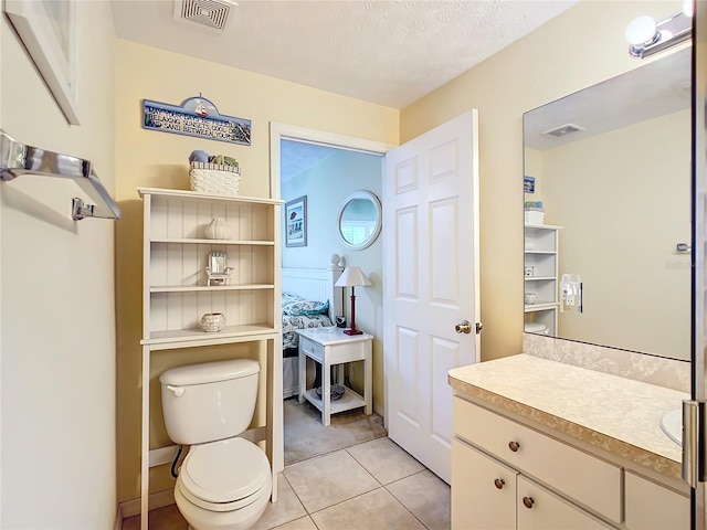 bathroom featuring a textured ceiling, vanity, toilet, and tile patterned floors