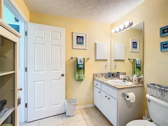 bathroom with a textured ceiling, vanity, toilet, and tile patterned floors