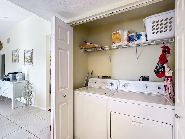 washroom with a textured ceiling, washer and clothes dryer, and light tile patterned flooring