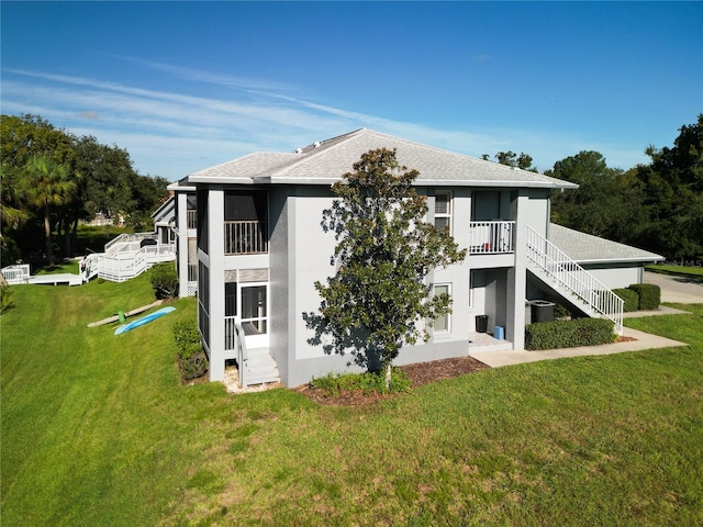 back of property featuring central AC, a yard, and a balcony