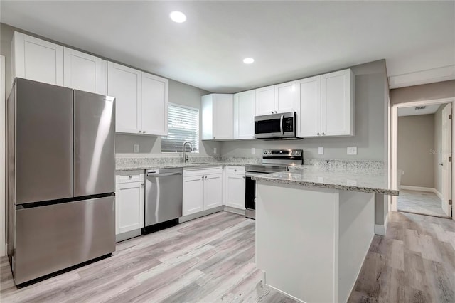 kitchen featuring white cabinetry, light hardwood / wood-style flooring, light stone counters, and stainless steel appliances