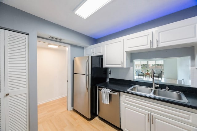 kitchen with stainless steel appliances, sink, light wood-type flooring, and white cabinetry