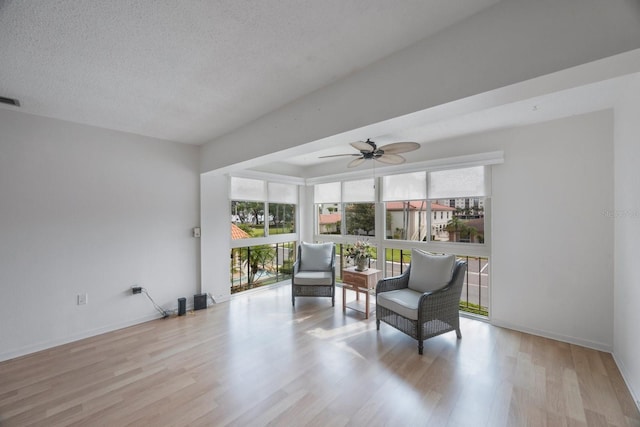 sitting room with a textured ceiling, ceiling fan, and light wood-type flooring