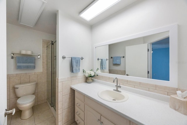 bathroom with tile patterned flooring, toilet, tile walls, a shower with shower door, and vanity