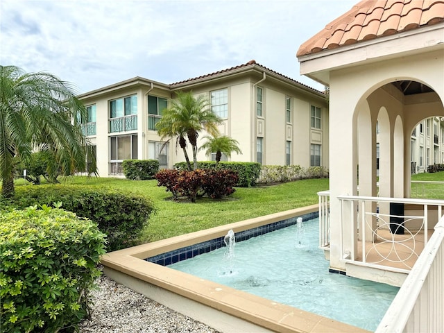 view of swimming pool with a lawn and pool water feature