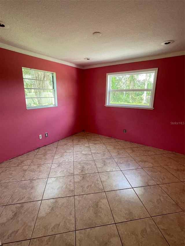 tiled empty room with a textured ceiling and crown molding