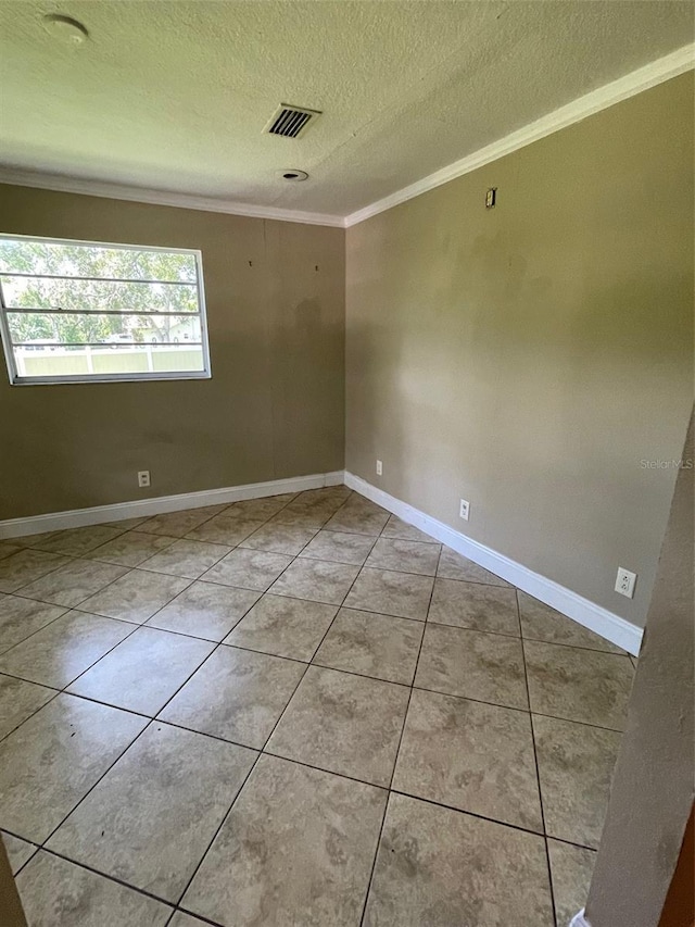 tiled empty room featuring a textured ceiling and ornamental molding