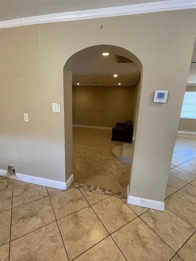 hallway featuring light tile patterned floors and crown molding