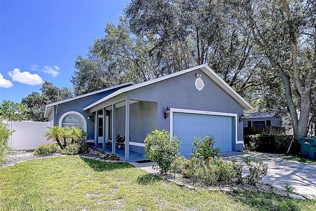 4477 67th St N, Saint Petersburg, FL 33709 - view of side of home with fence, a yard, concrete driveway, stucco siding, and a garage