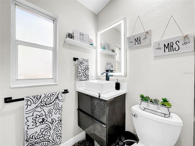 bathroom featuring toilet, plenty of natural light, and vanity