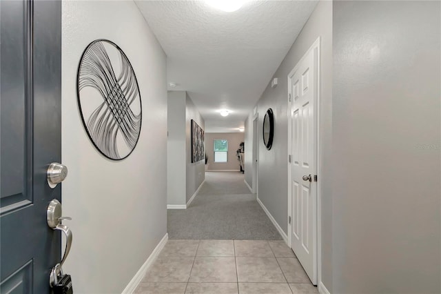 hall featuring a textured ceiling and light tile patterned floors