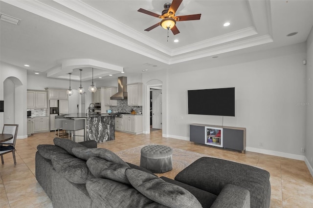 living room featuring a raised ceiling, ceiling fan, and crown molding