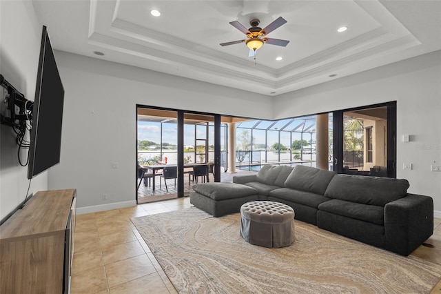 tiled living room with a raised ceiling, ceiling fan, crown molding, and a healthy amount of sunlight