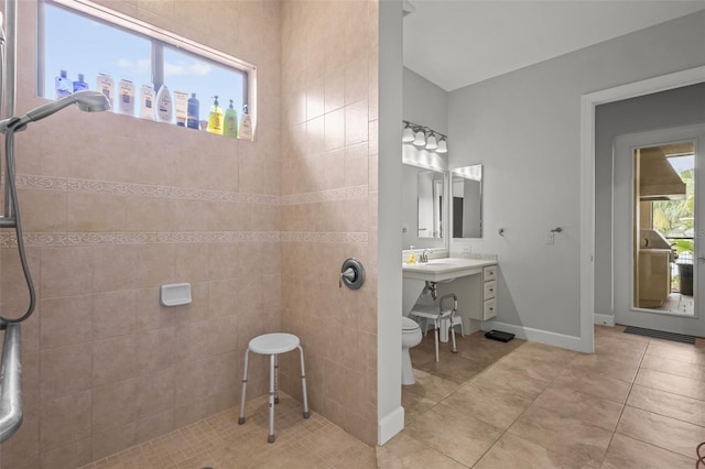 bathroom with tiled shower, tile patterned floors, toilet, and plenty of natural light