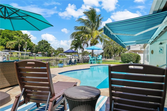 view of pool featuring a water view and a patio