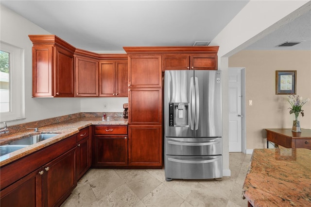 kitchen with sink, light stone counters, and stainless steel refrigerator with ice dispenser