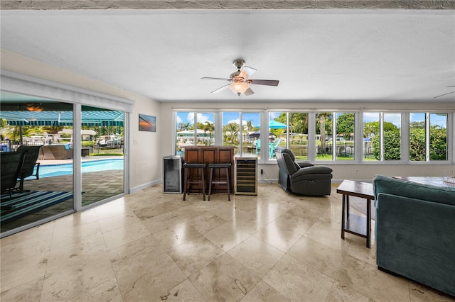 living room featuring plenty of natural light, ceiling fan, and beverage cooler