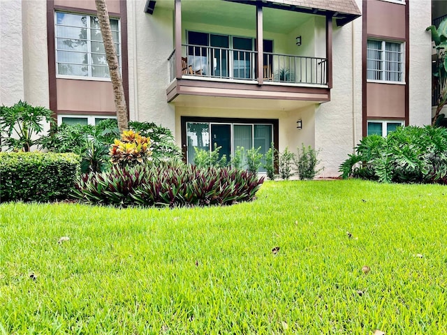 back of property with a yard and a balcony