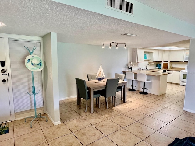 dining area with a textured ceiling, sink, and light tile patterned floors