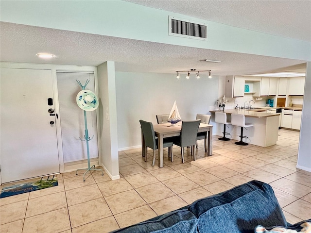 tiled dining area featuring sink and a textured ceiling