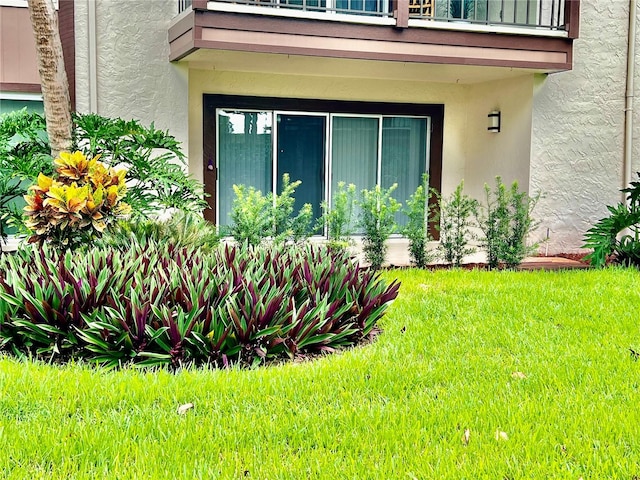 property entrance with a balcony and a lawn