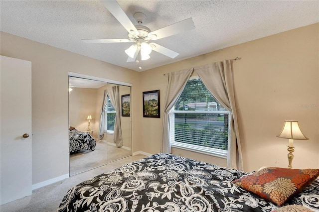 carpeted bedroom featuring multiple windows, a closet, ceiling fan, and a textured ceiling