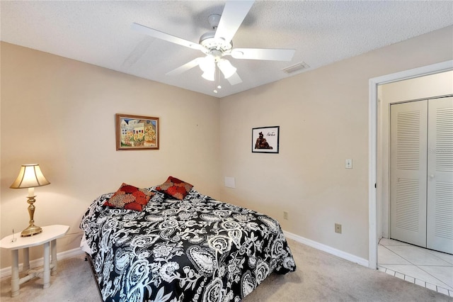 bedroom featuring light carpet, ceiling fan, and a textured ceiling