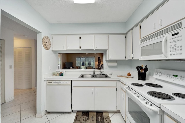 kitchen featuring sink, white appliances, a textured ceiling, white cabinets, and light tile patterned flooring