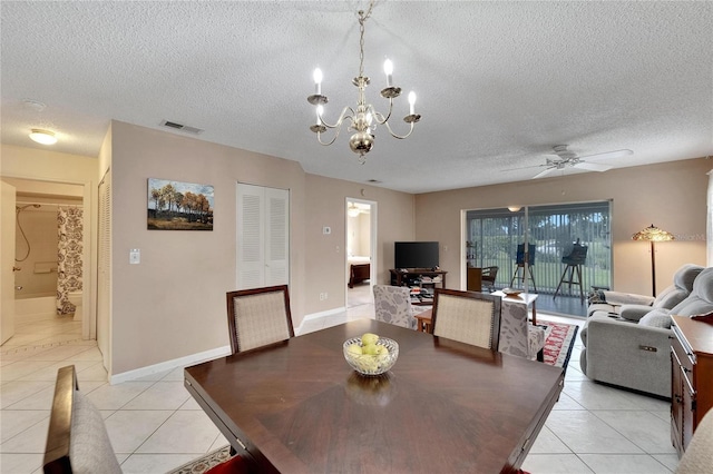 dining area with ceiling fan with notable chandelier, light tile patterned floors, and a textured ceiling