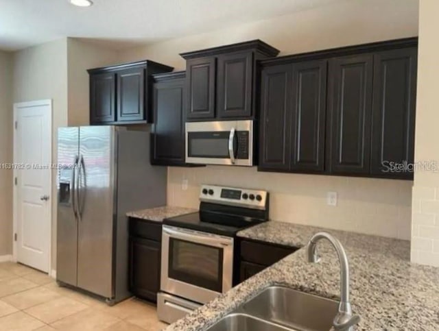 kitchen featuring light tile patterned floors, sink, light stone countertops, and appliances with stainless steel finishes