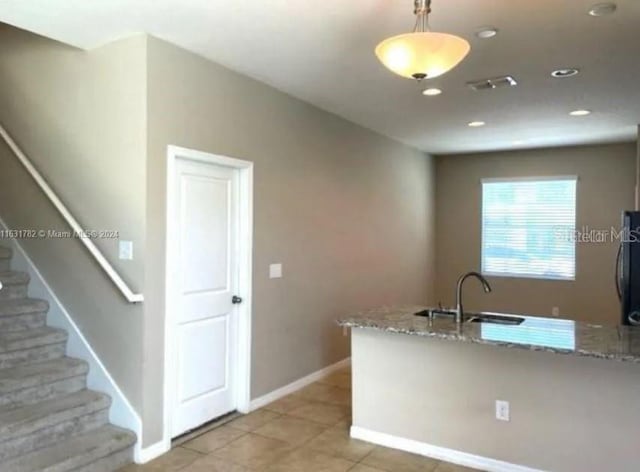 kitchen with hanging light fixtures, light stone counters, light tile patterned floors, and sink