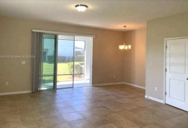 tiled spare room with an inviting chandelier