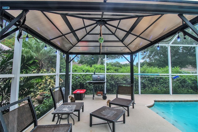 view of pool with glass enclosure, a grill, and a patio area