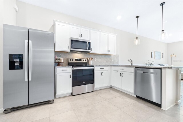 kitchen with decorative light fixtures, light stone counters, kitchen peninsula, appliances with stainless steel finishes, and white cabinets