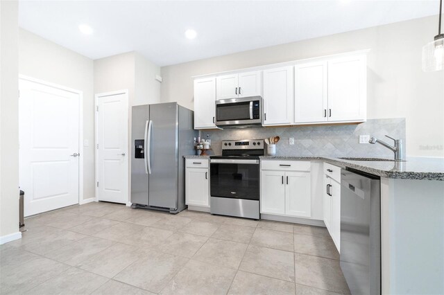 kitchen featuring white cabinets, light tile patterned floors, appliances with stainless steel finishes, stone countertops, and sink