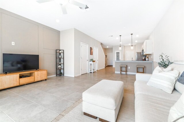 living room featuring sink, light tile patterned floors, and ceiling fan