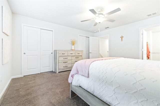 carpeted bedroom with two closets and ceiling fan