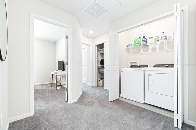 clothes washing area with washing machine and clothes dryer and light carpet