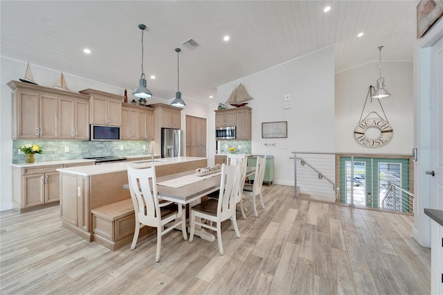 kitchen featuring pendant lighting, a center island, stainless steel appliances, and light wood-type flooring