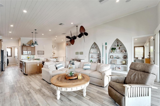 living room with sink, a high ceiling, and light hardwood / wood-style floors