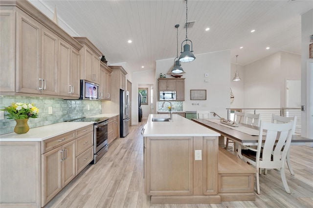 kitchen with light hardwood / wood-style flooring, a kitchen island with sink, stainless steel appliances, sink, and lofted ceiling